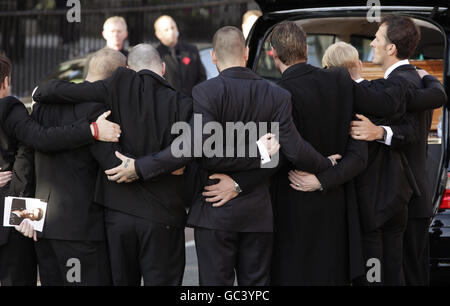 I portacolori della bara, compresi i membri di Boyzone Ronan Keating e Shane Lynch, abbracciano dopo i funerali di Stephen Gately alla chiesa di St Laurence o'Toole a Dublino. Foto Stock