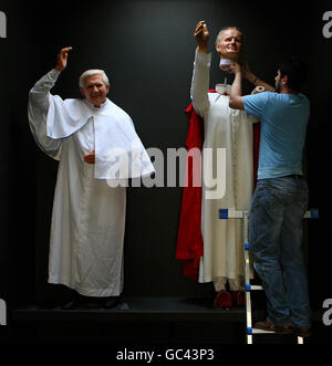 Danny Balan solleva la testa di cera di Papa Giovanni Paolo II in posizione accanto alle opere di cera dell'attuale Papa Benedetto XVI mentre si preparano i preparativi finali per l'apertura ufficiale del riaperto National Wax Museum Plus a Foster Place, Dublino. Foto Stock