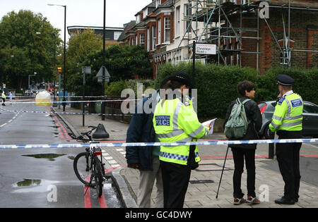 Gli ufficiali di polizia consigliano ai residenti locali mentre un'indagine si svolge vicino alla stazione ferroviaria di Clapton, nella parte est di Londra, dopo la uccisione fatale di un giovane. Foto Stock