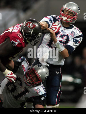 Tom Brady (a destra) dei patrioti del New England passa mentre il compagno di squadra Stephen Neal (in basso) blocca un placcaggio da Jimmy Wilkerson di Tampa Bay Buccaneers (a sinistra) durante la partita NFL al Wembley Stadium di Londra. Foto Stock