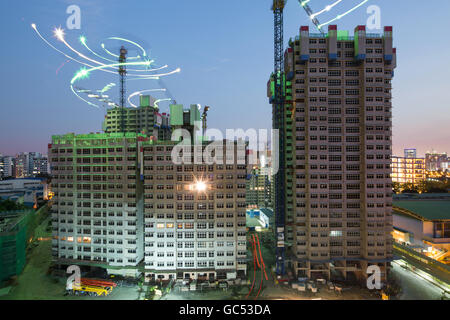 Lunga esposizione delle gru a torre che ruotano in un cantiere di abitazioni pubbliche in serata a Bukit Batok, Singapore. Foto Stock