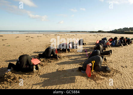 I manifestanti sul cambiamento climatico si sono vestiti di ministri delle finanze del G20 che seppelliscono la testa nella sabbia della spiaggia di West Sands a St Andrews mentre oltre venti ministri delle finanze di tutto il mondo si riuniscono al Fairmont Hotel, St Andrews, per la riunione dei ministri delle finanze del G20 e dei governatori delle banche centrali. Foto Stock