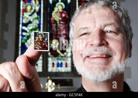 Il reverendo Neil Spencer ha un francobollo soffiato di fronte alla vetrata Henry Holiday della chiesa di St Michael a Ormesby, Norfolk, che presenta su un francobollo di prima classe dell'emissione del francobollo di Natale di Royal Mail, che oggi è in vendita. Foto Stock