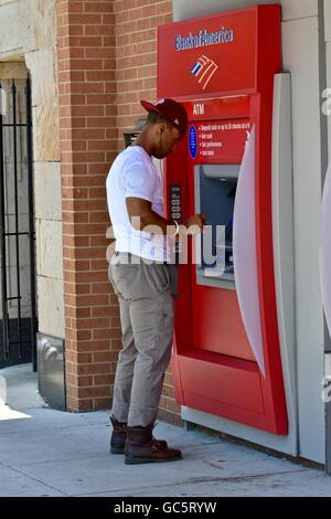 Un maschio di ottenere denaro contante al di fuori di un Bank of America ATM Foto Stock