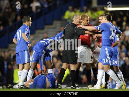 Calcio - Barclays Premier League - Chelsea / Manchester United - Stamford Bridge. I giocatori del Chelsea e del Manchester United discutono con l'arbitro Martin Atkinson mentre Ricardo Carvalho (a sinistra) del Chelsea si trova ferito in campo Foto Stock