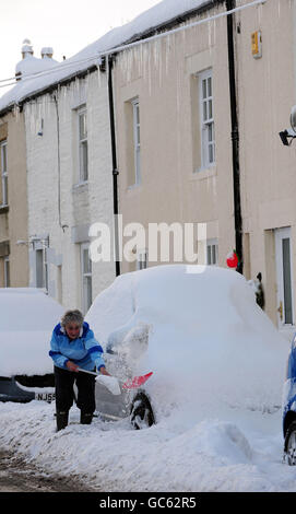 Una donna cerca di scavare la sua auto fuori ad Allendale, Northumberland dopo la caduta pesante della neve. Foto Stock