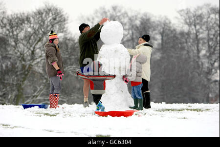 La famiglia Christie, della Nuova Zelanda, si prende il tempo di visitare la famiglia a Great Barr, Birmingham, per costruire un pupazzo di neve a Redhouse Park. Foto Stock