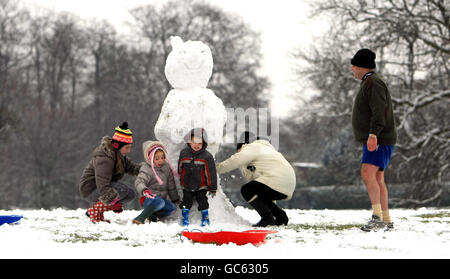 La famiglia Christie, della Nuova Zelanda, si prende il tempo di visitare la famiglia a Great Barr, Birmingham, per costruire un pupazzo di neve a Redhouse Park. Foto Stock