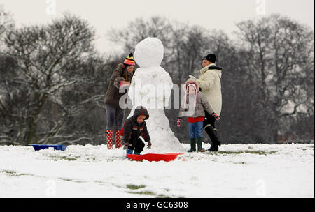 La famiglia Christie, della Nuova Zelanda, si prende il tempo di visitare la famiglia a Great Barr, Birmingham, per costruire un pupazzo di neve a Redhouse Park. Foto Stock