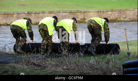 Gli ingegneri reali preparano la terra accanto al fiume Derwent a Workington, Cumbria, prima di costruire un ponte pedonale temporaneo per ricongiungersi ai lati nord e sud della città i cui legami principali sono stati interrotti a seguito del crollo del ponte Northside e della chiusura del ponte Calva, che rimane instabile e pericoloso a seguito di inondazioni. Foto Stock