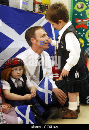 Jim Murphy, Segretario di Stato per la Scozia, ha il suo volto dipinto con un salti, durante una visita al vivaio del Madras Family Center a Neilston per celebrare il giorno di Sant'Andrea. Foto Stock