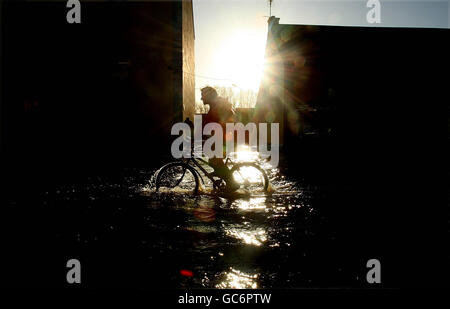 Un uomo corre in bicicletta attraverso l'alluvione su River Street, Ballinasloe in Co.Galway che è sotto i 3 piedi di acqua dopo che il fiume suck ha scoppiato le sue rive dopo la pioggia pesante durante la notte, più pioggia è prevista questo fine settimana. Foto Stock