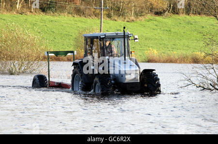 Un agricoltore sulla strada allagata di Samsonagh vicino a Co Fermanagh, dopo che la zona ha sofferto oltre 30 giorni di pioggia consecutiva con il fiume Lough Erne riferito di essere al suo più alto in memoria vivente. Foto Stock