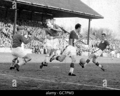 L'Alan A'Court di Liverpool, a destra, spara per il gol, ma la palla è scrambled via. George Wright di Leyton Orient, secondo a sinistra, guarda con ansia il portiere Frank George, a sinistra. Foto Stock