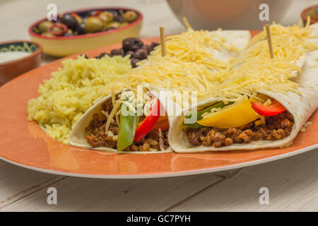 Burrito riempiti con carne macinata di manzo e peperoni con riso e fagioli neri sul lato Foto Stock