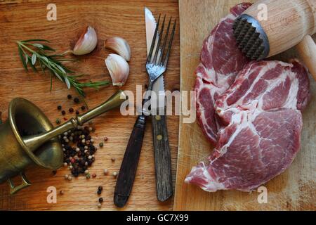 La carne cruda. Bistecca di carne di maiale con erbe aromatiche Foto Stock