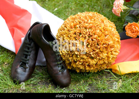 Coppia di vecchi scarpini da calcio e una sfera realizzata dai fiori Foto Stock