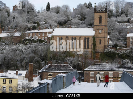 La gente cammina sulla neve sopra il ponte di ferro a Ironbridge, Shropshire, mentre la nevicata continua attraverso la maggior parte del Regno Unito. Foto Stock