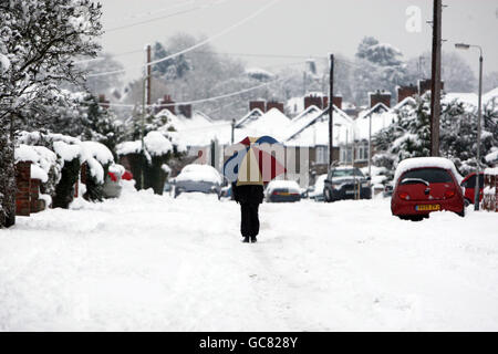 La gente cammina invece di usare l'auto a Reading, Berkshire come la neve colpisce la contea. Foto Stock