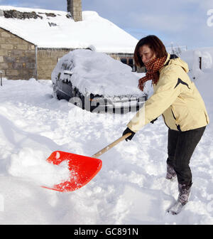 Anne Wilson libera la neve dal suo vialetto di Corvichen, Scozia, mentre la neve e il ghiaccio continuavano a causare il caos in tutta la Gran Bretagna. Foto Stock