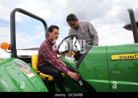 Il Presidente messicano Enrique Peña Nieto, seduti, viene illustrato come utilizzare un trattore John Deere di Michoacan governatore Silvano Aureoles durante una cerimonia a consegnare 600 trattori agricoli per gli agricoltori poveri Luglio 5, 2016 in La Goleta, Charo, Michoacan, Messico. Il programma di governo prevede di fornire 25.000 trattori gli agricoltori poveri entro il 2018 con la speranza di migliorare la produzione agricola in tutta la nazione. Foto Stock