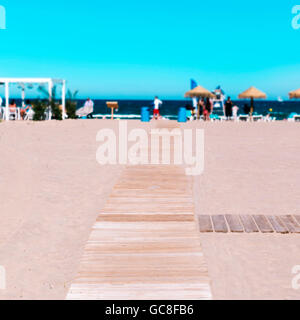 Passerella in legno a la spiaggia di Malvarrosa di Valencia, Spagna, con il mare Mediterraneo e irriconoscibile lucertole da mare nella parte posteriore Foto Stock