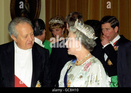 IL PRINCIPE DI GALLES SEMBRA PREMUROSO, IN QUANTO LA REGINA E LA MOGLIE ESTRANDA, LA PRINCIPESSA DI GALLES, PARLANO CON GLI OSPITI DURANTE UN BANCHETTO ALL'AMBASCIATA PORTOGHESE DI LONDRA. Foto Stock