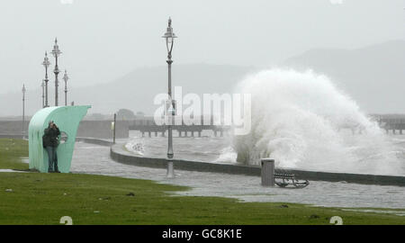 Un membro del pubblico fotografa onde che si infrangono contro la passeggiata a Clontarf, nel nord di Dublino, mentre le cattive condizioni atmosferiche continuavano a causare pericolose condizioni di guida in tutto il paese. Foto Stock