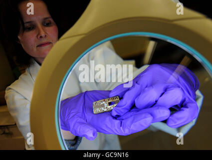 Il Registrar Sam Richardson ha un granato dorato a forma di H sotto una lente d'ingrandimento, uno dei nuovi 40 pezzi aggiunti allo Staffordshire Hoard, che sarà esposto al Potteries Museum di Stoke on Trent, Staffordshire. Foto Stock