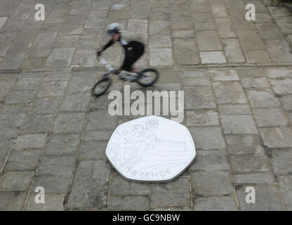 Theo Crutchley-Mack, 16 da Halifax, Posa sulla sua moto accanto a una versione gigante di un pezzo da 50 pence con il suo design di un pilota che corre una moto in un Velodrome come è stato annunciato oggi che aveva vinto un concorso nazionale scuola secondaria organizzato dalla Royal Mint per creare un Giochi Olimpici di Londra Ciclismo a tema 50p, presso la scuola di Rishworth a Halifax. Foto Stock