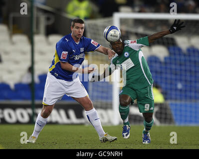 L'Arron Mclean di Peterborough United sfida il pallone dell'Anthony Gerrard di Cardiff durante la partita del campionato Coca-Cola al Cardiff City Stadium di Cardiff. Foto Stock