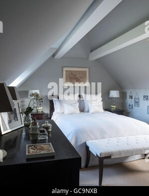 Camera da letto con soffitto spiovente. Le pareti dipinte in rovere Apple da terra cotti. Letto da Lombok. Cuscini imbottiti in tessuto Foto Stock