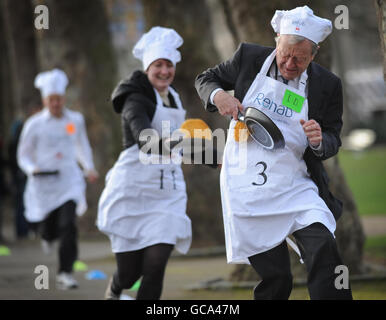 Lord Dubs (a destra) e Allegra Stratton (al centro) del Guardiano gareggiano nella corsa parlamentare annuale di Pancake a Westminster, Londra, insieme ad altri giornalisti, parlamentari e membri della Camera dei Lord, per raccogliere fondi per la carità Rehab e per sensibilizzare il pubblico sul suo lavoro per le persone con disabilità. Foto Stock