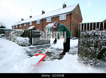 Robert Allen libera la neve intorno al suo azionamento in Great Chart vicino Ashford, Kent dopo una notte di caduta pesante della neve. Foto Stock