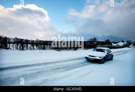 Un autista si fa strada attraverso Great Chart vicino Ashford, Kent, dopo una notte di forte caduta di neve. Foto Stock