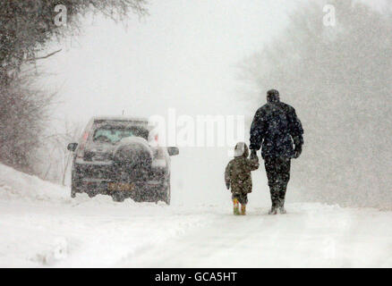 Tempo invernale Feb. La gente cammina attraverso Great Chart vicino ad Ashford, Kent, dopo una notte di nevicate pesanti. Foto Stock