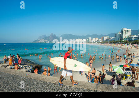 RIO DE JANEIRO - Febbraio 21, 2015: Carioca surfista brasiliano passeggiate con tavola da surf su un mattino luminoso in corrispondenza di Arpoador. Foto Stock