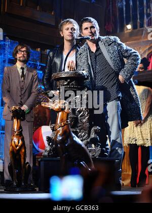 Dominic Howard (centro a sinistra) e Matt Bellamy (centro a destra) di Muse sul palco per raccogliere il premio Best British Band ai NME Awards 2010 all'O2 Academy Brixton, Londra Foto Stock