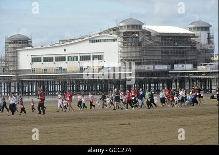 I corridori passano davanti al Grand Pier di Weston-super-Mare mentre prendono parte alla corsa di beneficenza in Sainsbury's Sport Relief Mile. Foto Stock