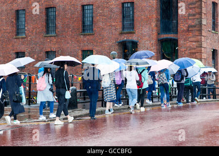 Pioggia pesante, Liverpool. Regno Unito: Meteo 09-luglio-2016. Piogge torrenziali acquazzoni benvenuti a centinaia di studenti stranieri come fanno visita l'Albert Dock di Liverpool. Con temperature al di sotto della media stagionale & cool docce pesanti al di sopra della regione, il meteo non mostra alcun segno di locazione per i visitatori. Credito: Cernan Elias/Alamy Live News Foto Stock