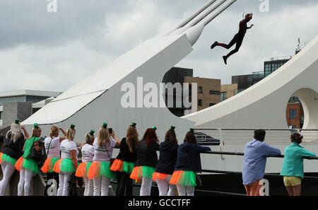 Un giovane uomo in una muta salti dal Samuel Beckett ponte nel fiume Liffey a Dublino come i passanti a guardare. Foto Stock