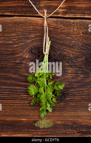 Coriandolo fresco anche sapere come coriandolo o prezzemolo cinese appeso sul legno rustico sfondo. Delizie di erbe aromatiche. Foto Stock