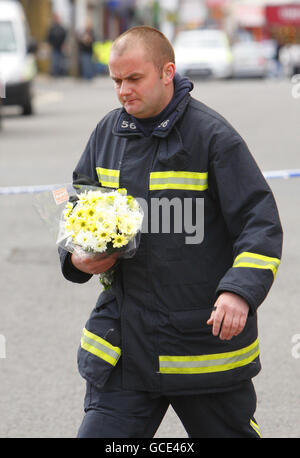 Un vigile del fuoco depone fiori ai piedi delle Shirley Towers a Southampton, dopo che i vigili del fuoco Alan Bannon e James Shears sono stati uccisi durante un incendio nel blocco di appartamenti nella zona di Shirley della città durante la notte. Foto Stock