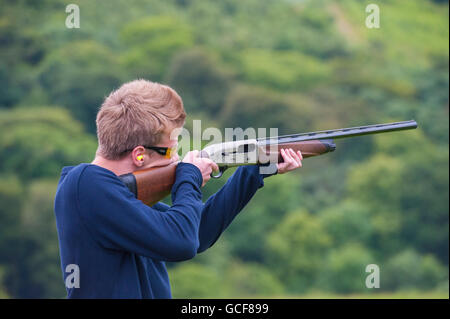 Un ragazzo adolescente spara Clay piccioni con una Beretta semi fucile automatico Foto Stock
