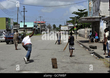 Un ragazzo pipistra in una partita di cricket di strada a Georgetown, Guyana. Foto Stock