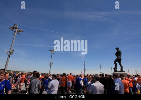 I fan di Blackpool e Cardiff City si riuniscono intorno al Sir Bobby Statua di Moore fuori Wembley Stadium prima della partita Foto Stock