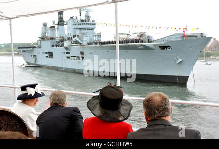 La Regina Elisabetta II della Gran Bretagna si rivolge a parlare con il primo ministro canadese Stephen Harper, (a sinistra) mentre passano l'HMS Ark Royal durante una revisione navale per celebrare il 100 ° anniversario della Marina canadese, nelle acque al largo di Halifax in Nuova Scozia, Canada. Foto Stock