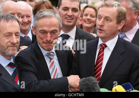 Fine Gael leader Enda Kenny (centro destra) scuote la mano di Richard Bruton (centro sinistra) sulla base della Leinster House, dopo aver vinto il voto in una riunione decisiva del partito parlamentare per la leadership del partito. Foto Stock