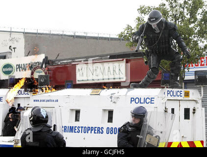 Un ufficiale di polizia salta per evitare una bomba a benzina durante gli scontri con i manifestanti nazionalisti dopo che una marcia arancione passò attraverso l'area stradale di Ardoyne a nord di Belfast. Foto Stock