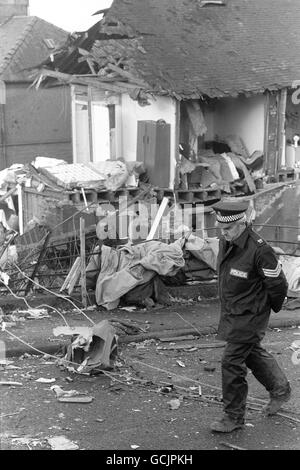 Un ufficiale di polizia si erge guardia sulle case naufragate nel crash di Pan am Boeing 747 Lockerbie, che ha ucciso tutti i 258 a bordo e 17 persone a terra. Foto Stock